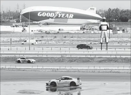  ?? Myung J. Chun Los Angeles Times ?? TEST TRACKS at Porsche’s center in Carson are across the 405 Freeway from the Goodyear blimp facility. Areas at what the firm calls a “53-acre sports car playground” include a twisty-turny “handling circuit” and an “accelerati­on straight” that...