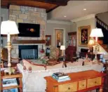  ??  ?? A stone   replace is the focal point of the spacious den; the wood ceiling adds to the rustic style.