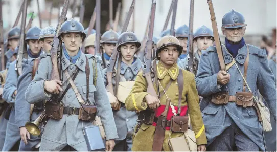  ?? AP PHOTOS ?? ‘WAR IS NEVER A GOOD THING’: People dressed in WWI uniforms, top, stand during a parade, which included the American flag, as part of a reconstruc­tion of the WWI battle of Verdun. Men dressed in WWI uniforms march, above, and take part in a re-enactment, top right.