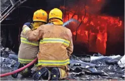  ??  ?? Firemen battle a blaze in a garage in the Sharq Industrial area.