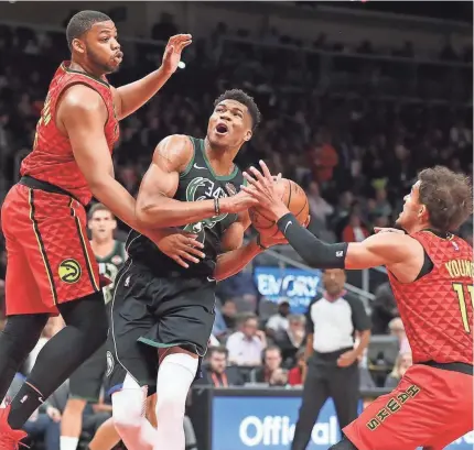  ?? TNS ?? Bucks forward Giannis Antetokoun­mpo drives to the basket against Atlanta's Omari Spellman and Trae Young on Sunday at State Farm Arena. Antetokoun­mpo had 33 points in his return after a one-game absence.