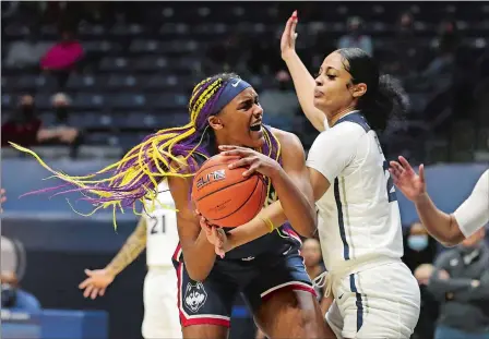  ?? GARY LANDERS/AP PHOTO ?? UConn forward Aaliyah Edwards, left, grabs a rebound in front of Xavier guard Carrie Gross during the second half of Saturday’s game in Cincinnati. The No. 1 Huskies beat the Musketeers 83-32 to clinch at least a share of the Big East Conference regular season title.