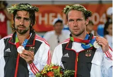  ??  ?? Nicolas Kiefer (links) und Rainer Schüttler präsentier­en mit leerem Blick ihre Silber medaillen 2004 in Athen.