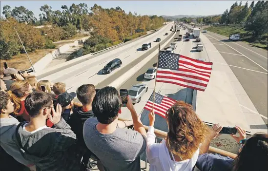  ?? Al Seib Los Angeles Times ?? JAKE POPPEN and his mother, Joell, wave flags as they watch the casket of Ventura County Sheriff's Sgt. Ron Helus pass beneath them on the 101 Freeway.
