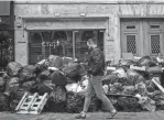  ?? LEWIS JOLY/AP ?? A man walks past uncollecte­d garbage Monday in Paris. Sanitation workers were on strike for a ninth day Tuesday, resulting in tons of garbage piling up along Paris sidewalks and streets.