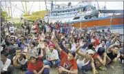  ?? DITAALANGK­ARA/ASSOCIATED PRESS ?? Burmese fishermen Friday at the Pusaka Benjina Resources fishing company in Benjina, Aru Islands, Indonesia, raise their hands when asked who wanted to return home.