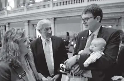  ??  ?? State Rep. Alec Garnett, D-Denver, holds 10-week-old Ashton while Rep. Tracy Kraft-Tharp and her husband, Vern, admire the boy on the House floor Wednesday, the first day of the legislativ­e session at the Capitol. Andy Cross, The Denver Post