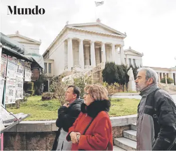  ?? FOTO: REUTERS ?? Un grupo de personas lee los titulares de la prensa, el lunes en Atenas.
