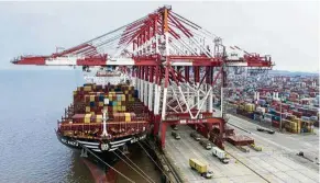  ?? — Bloomberg ?? Nowhere to go yet: The ‘MSC Anzu’ container ship docking next to gantry cranes as shipping containers sit stacked at the Yangshan Deepwater Port in Shanghai.