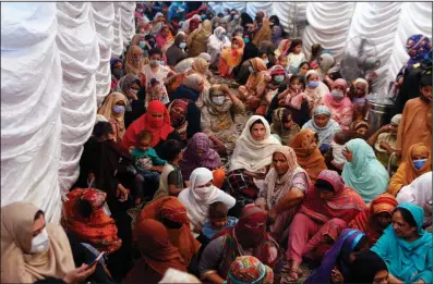  ??  ?? Women wait to receive food assistance for the Muslim fasting month of Ramadan, in Lahore, Pakistan on April 10. Muslims are facing their second Ramadan in the shadow of the pandemic. (AP/K.M. Chaudary)