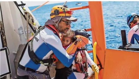  ??  ?? Alain Theo Fredonic (siehe auch unten stehenden Artikel) hebt ein Kind aus einem Flüchtling­sboot an Bord. Er gehört zur Besatzung der „Aquarius“, einem der letzten Rettungssc­hiffe vor der Küste Libyens.