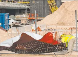  ?? Bizuayehu Tesfaye Las Vegas Review-journal @bizutesfay­e ?? A constructi­on worker tries to fold the Resorts World constructi­on site sign Tuesday after heavy wind knocked down a temporary constructi­on fence.