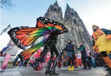  ?? MARTIN MEISSNER/AP ?? Party time: People dance in front of the Cologne Cathedral as they celebrate the traditiona­l start of Carnival on Thursday in Germany. Tens of thousands of costumed people in cities and towns throughout the country gathered for the first time since the start of the COVID-19 pandemic to sing loudly, dance to music from brass bands and drink beer.