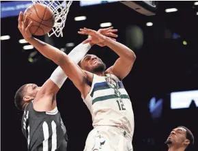  ??  ?? Jabari Parker sneaks a shot around Nets center Jahlil Okafor on Sunday. Parker scored 11 points in 24 minutes in his second game back.