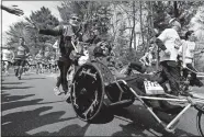  ?? MICHAEL DWYER, FILE/AP PHOTO ?? Rick Hoyt, center, is pushed by his father Dick, along the Boston Marathon course in 2013 in Wellesley, Mass.