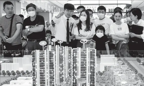  ?? ZHAO QIRUI / FOR CHINA DAILY ?? Potential homebuyers check housing models at a real estate agency in Huaian, Jiangsu province, in June.