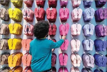  ?? NELSON ALMEIDA/AFP ?? An employee touches a pair of Brazilian Havaianas flip-flops at a store in Sao Paulo, Brazil, on Tuesday.