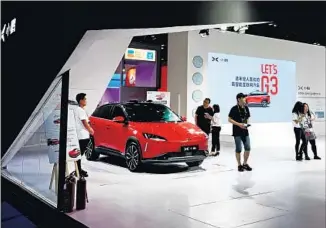  ?? AFP/Getty Images ?? CHINESE PEOPLE look at an electric vehicle made by Xpeng during the Global Mobile Internet Conference in Beijing. The EV start-up has earned the backing of several Chinese tech giants.