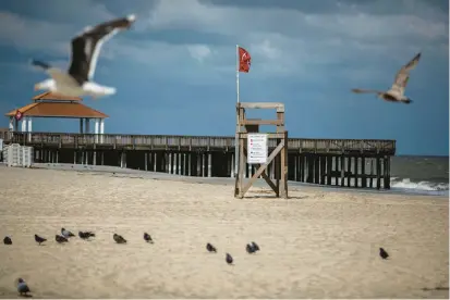  ?? KENDALL WARNER/STAFF ?? Birds fly around Buckroe Beach in Hampton in August as a red flag signals the beach is closed for swimming as Idalia approaches. A hurricane that caused $1 billion in damage, Idalia arrived in Hampton Roads as a weakened tropical storm.