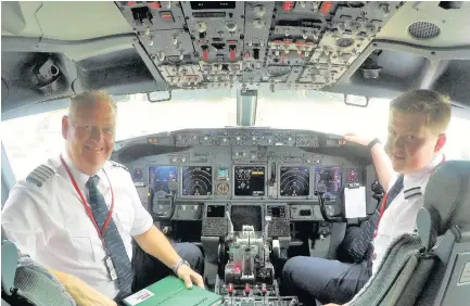  ??  ?? > Captain David Kempton and his co-pilot son Alex in the Boeing 737-800 at Birmingham Airport