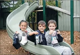 ?? ?? Helping hand: St Mel’s Kindergart­en students Stella Collier, Mario Campi and Wyatt Dodd with some of the new socks donated so far.