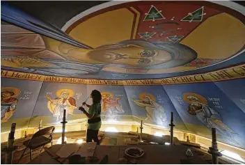  ?? Melissa Phillip / Houston Chronicle ?? Artist Erin Kimmett puts the finishing touches on the icons on the dome of St. Anthony the Great.