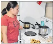 ?? ERIC MCCARTHY/JOURNAL PIONEER ?? Angel Aylward keeps careful watch on a pot as she cooks up some lumpia, a Filipino dish that includes ground pork and chopped vegetables all rolled up in a wrapper and deep-fried.