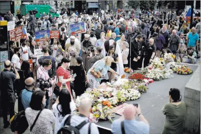  ?? Matt Dunham ?? The Associated Press People look at flowers laid after a minute’s silence Sunday on London Bridge to mark the one-year anniversar­y of the attack that happened there. Eight people were killed and nearly 50 injured.