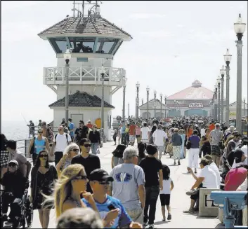  ?? Armando Brown The Associated Press file ?? Pedestrian­s walk along the Huntington Beach Pier in Huntington Beach, Calif.