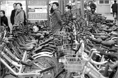  ??  ?? Waiting for a bus at a bus station filled with shared bicycles in Beijing.