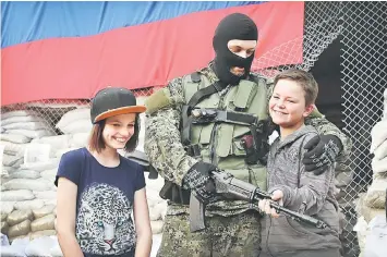  ??  ?? A 12-year-old boy and girl pose for a picture with pro-Russian militant outside the city council building in Donetsk, Ukraine. — AFP photo