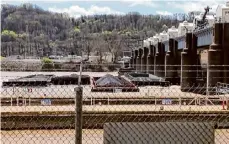  ?? WTAE via Associated Press ?? A number of barges sit pinned against the Emsworth lock and dam in Pittsburgh on Saturday. More than two dozen river barges broke loose from their moorings and floated down the Ohio River, damaging a marina and striking a bridge.