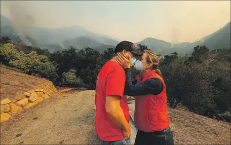  ?? Mel Melcon Los Angeles Times ?? AS THE Thomas fire burns in the background, Dan Bellaart and his wife, Mary McEwen, comfort each other at their Montecito home.