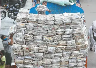  ?? EPA-Yonhap ?? Indian laborers load old papers bundles at a city market area in Bangalore, India, Thursday. India is the third-hardest-hit country by the pandemic after the United States and Brazil.