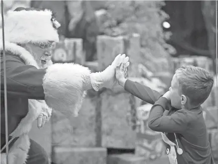  ?? KYLE ROBERTSON/COLUMBUS DISPATCH ?? Decker Dowdy, 3, touches Santa through a “magic shield” at the Polaris Cabela’s on Nov. 10. The store requires timed appointmen­ts to see the jolly old elf.