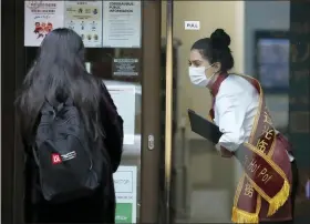  ?? FRANK AUGSTEIN — THE ASSOCIATED PRESS ?? A waiter of a Chinese restaurant wearing a face mask welcomes a customer in London.