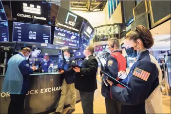  ?? Courtney Crow / New York Stock Exchange via Associated Press ?? In this photo provided by the New York Stock Exchange, trader Samantha Tavares, right, works with colleagues on the floor on Wednesday. In response to stock market volatility surroundin­g companies such as GameStop, Greenwich-based brokerage Interactiv­e Brokers Group announced new trading restrictio­ns affecting stocks and options of GameStop and several other companies.