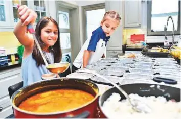  ?? Clint Egbert/Gulf News ?? Rima Karam’s children help in packing iftar items to be distribute­d at the nearby mosque.