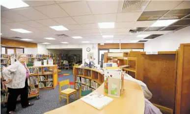  ?? PHOTOS BY LUIS SÁNCHEZ SATURNO/THE NEW MEXICAN ?? Patricia Hodapp, director of libraries, looks at the water damage to the La Farge Branch Library on Aug. 1. U.S. Rep. Ben Ray Luján has secured 1,500 books for the library following the July flood.