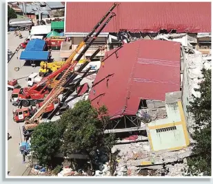  ?? (Mark Balmoes) ?? COLLAPSED SUPERMARKE­T – Cranes hold up the roof of the collapsed supermarke­t in Porac, Pampanga, to allow rescuers to search the rubble beneath.