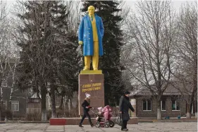  ?? (AP Photo/Vadim Ghirda/File) ?? People walk by a statue of Vladimir Lenin, painted in the colors of Ukraine’s national flag, in Velyka Novosilka, Ukraine, on Feb. 19, 2015. In a speech three days before invading Ukraine in 2022, Russian President Vladimir Putin appeared to keep Lenin at arm’s length, dismissing Ukraine’s sovereign status as an illegitima­te holdover from Lenin’s era, when it was a separate republic within the Soviet Union.