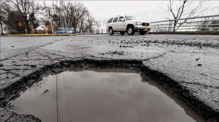  ?? Photos by Will Waldron / Times Union ?? A pothole in the middle of Northern Boulevard in Albany grows deeper as the winter’s freeze and thaw cycles continue. The Consolidat­ed Local Highway Improvemen­t Program, or CHIPS, and the PAVE NY initiative are not getting funding increases under Gov. Kathy Hochul’s proposed state budget.