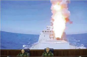  ?? AP FOTO ?? SYRIA WAR. Colonel General Sergei Surovikin, Commander of the Russian forces in Syria, left, attends a briefing in Moscow as a screen in the back shows the Russian navy launching a cruise missile at the Islamic state in Syria.