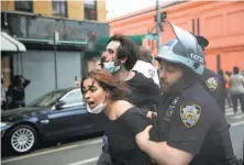  ?? Seth Wenig / Associated Press ?? Police officers restrain protesters in Brooklyn. Health experts are worried about the spread of the coronaviru­s in the crowds.
