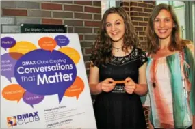  ??  ?? Singer, songwriter Whitney Woerz and her mom, Chrissy, look over DMAX’s promotion materials including their signature wrist bands.