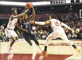  ?? Michael Perez / Associated Press ?? UConn’s Tarin Smith (2) drives to the basket against Temple’s Shizz Alston Jr. (10) and Nate Pierre-Louis (15) on Wednesday night in Philadelph­ia.