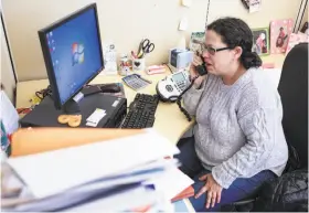  ?? Amy Osborne / Special to The Chronicle ?? Benefits counselor Ellen Novogrodsk­y of the San Francisco AIDS Foundation, which helps patients who need access to life-saving medication­s, places a call to the state health department.