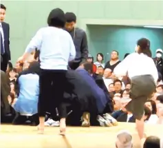  ??  ?? File photo grab from aYouTube video shows women climbing up a sumo ring to treat Maizuru city mayor Ryozo Tatami, who collapsed while making a speech in a gym in Maizuru, Kyoto prefecture. — Reuters photo