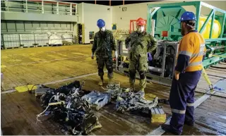  ?? CMDR. ROBERT WATT DEPARTMENT OF NATIONAL DEFENCE ?? Canadian Armed Forces members inspect recovered parts of the helicopter Stalker 22 during recovery operations for the aircraft in the Mediterran­ean Sea on Sunday.