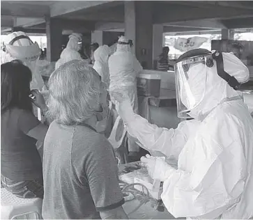  ??  ?? Health workers collect throat swab samples from vendors during the recent “surveillan­ce testing” for coronaviru­s disease 2019 in Bacolod City.